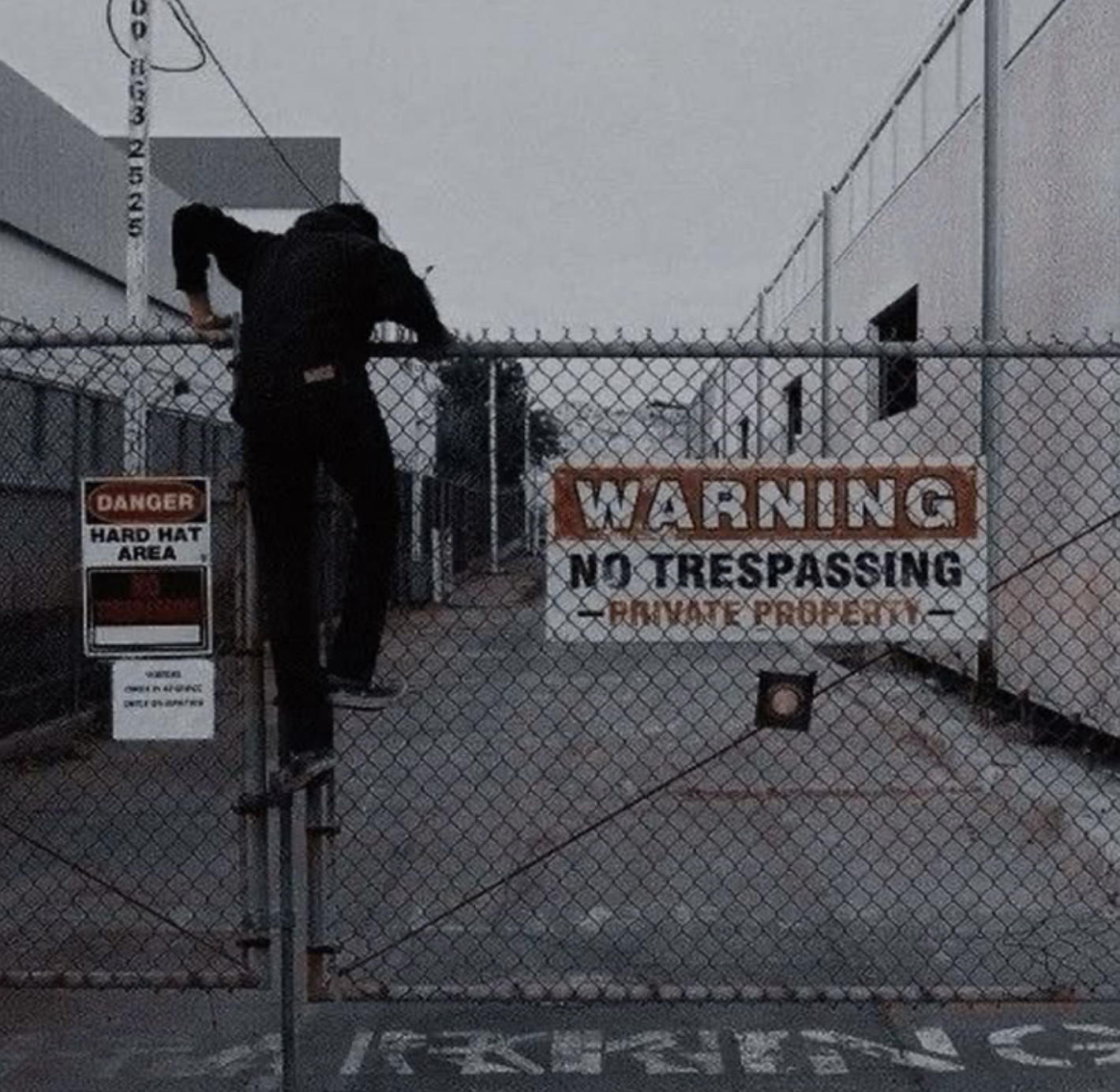 Guy climbing over a fence with a sign on it that says Warning No Tresspassing Private Property